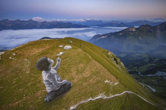 Pintura de un niño en una montaña creando nubes con un pombero de burbujas de jabón