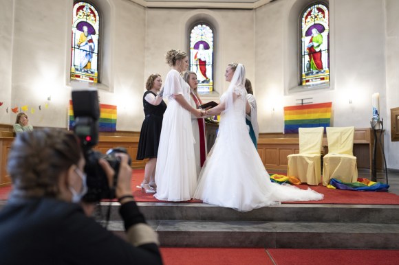 Two women in white wedding dresses in a church