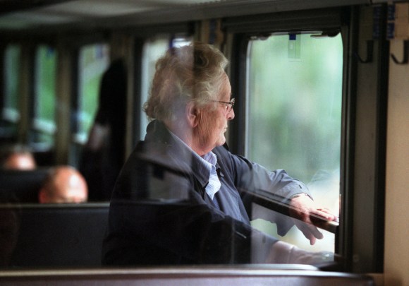 Una jubilada observa a través de la ventanilla de un tren