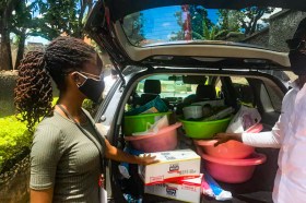 Two people next to a car loaded with a series of products and the trunk is open