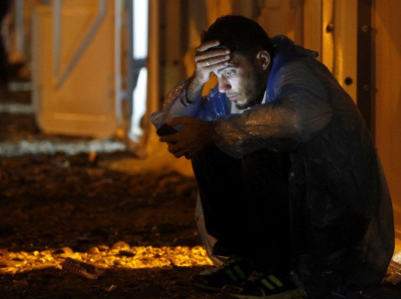 un migrant dans le noir regarde son smartphone