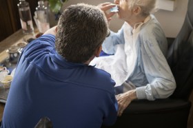 Nurse administering medication to an elderly person