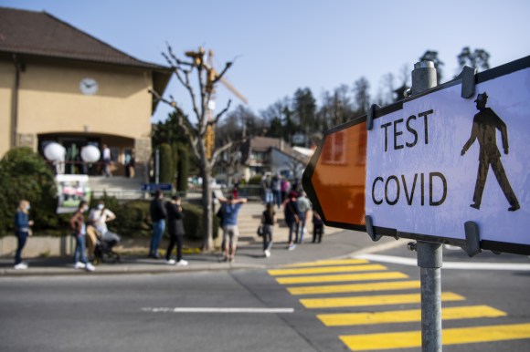 Sign for Covid test centre and people queuing outside