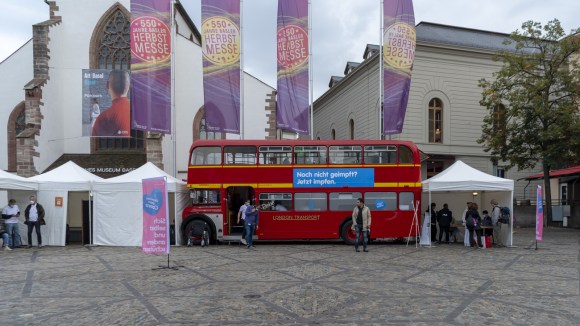 A public square with a red bus and information tents