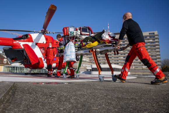 Rega medical helicopter with staff moving a Covid patient