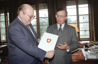 スイスが署名した第8回多国間通商交渉「ウルグアイ・ラウンド」の合意書を見せるフィリップ・ロシエWTO大使（右）とレナート・ルジェロWTO事務局長（左）。 写真は1995年6月1日、ジュネーブのWTO本部で撮影された