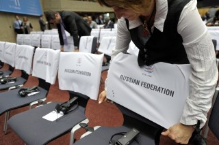 A WTO staff adds the Russian Federation name to the seats for the delegation members.