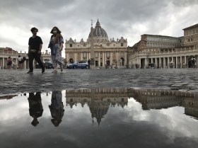 سائحان يتنزهان في ساحة القديس بطرس المبللة بالأمطار في الفاتيكان