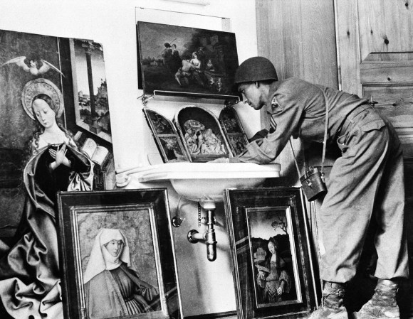 Ein Soldat beugt sich vor und betrachtet Kunstwerke