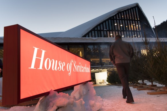 Man walks past House of Switzerland sign in the snow