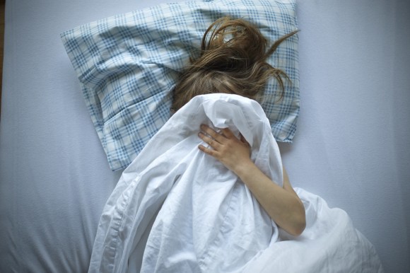 Child cowers under bedclothes
