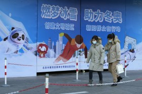 Passersby in front of posters for Beijing Winter Olympics