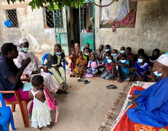 In front of the children and their Koranic teacher (right), instructor Mohammed Sankhe (left) insists on the universal right to education, explains what constitutes abuse and reminds them that corporal punishment is forbidden. (SWI swissinfo.ch / Pauline Turuban) Enfants assis écoutant un formateur