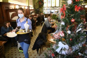 Waitress wearing a mask serves food ina restaurant
