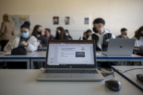 Masked pupils sit behind a teacher s computer