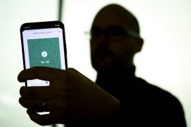 Shadowy person displays Covid certificate on smartphone