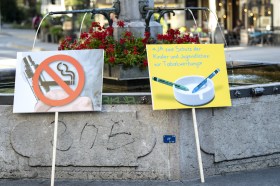 Two anti-tobacco advert placards leaning against public fountain