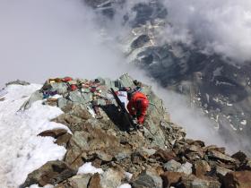 Man installing measuring equipment amid rocky summit