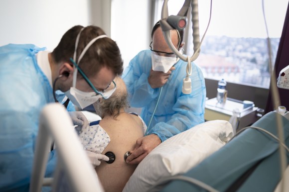 Two doctors examine a patient s breathing