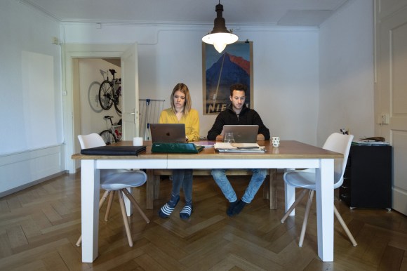 Woman and man with computer laptops at a table in an apartment