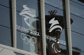 Olympic Tower reflected in a window with logo of the Beijing Winter Games