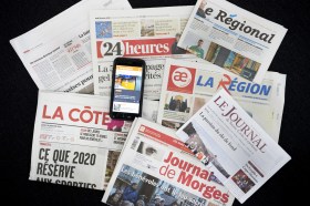 Front pages of French-language newspapers and a mobile phone with screen