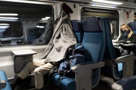 رجل ينام في قطار ويغطي رأسه بسترته