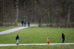 رجال ونساء أطفال يتنزهون على ألأقدام أو فوق دراجات في منطقة خضراء
