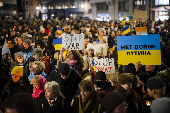 عشرات النساء والرجال يرفعون لافتات مناهضة للحرب وأعلام أوكرانيا