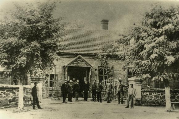 صورة بالأبيض والأسود لمجموعة من الرجال أمام بوابة مبنى