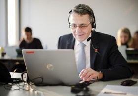 President Cassis at desk with computer and headset