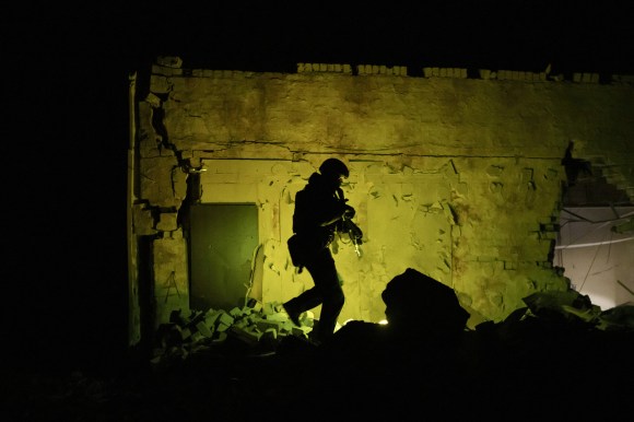 Ukrainian soldier walks next to wall.