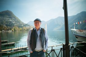 Man in a cap in front of Lake Lugano