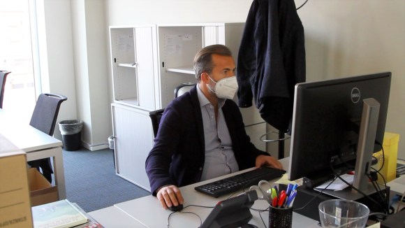 homme portant un masque dans son bureau devant un ordinateur