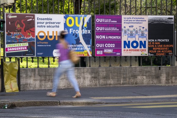 Woman walks in front of vote posters.