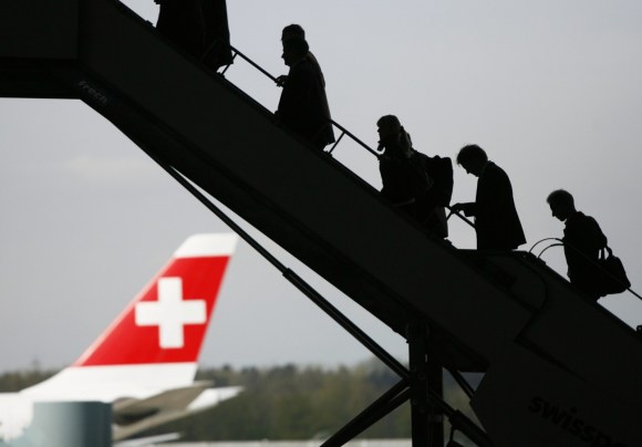 Passageiros abordando uma aeronave, porta-aviões suíço atrás