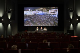 Cinema screen and three people on podium