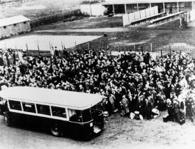 Un vehículo y una multitud de personas que serán deportadas