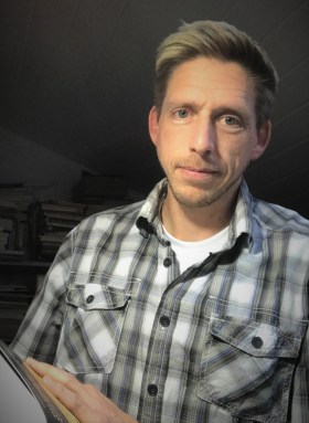 Homme avec une chemise à carreaux et portant un livre