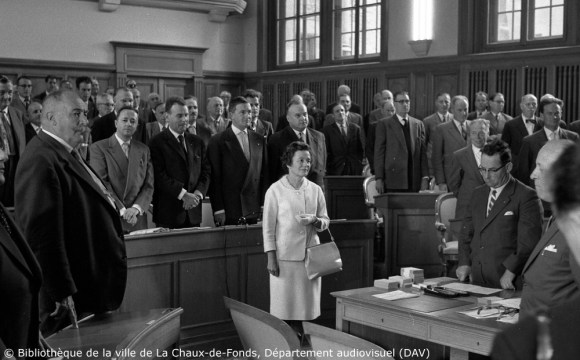 Una mujer jura su cargo en una cámara parlamentaria llena de hombres.
