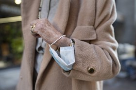 Une femme âgée porte un masque au bras