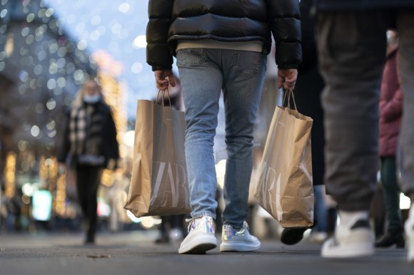 Imagen parcial de una persona caminando por la calle con bolsas de compras