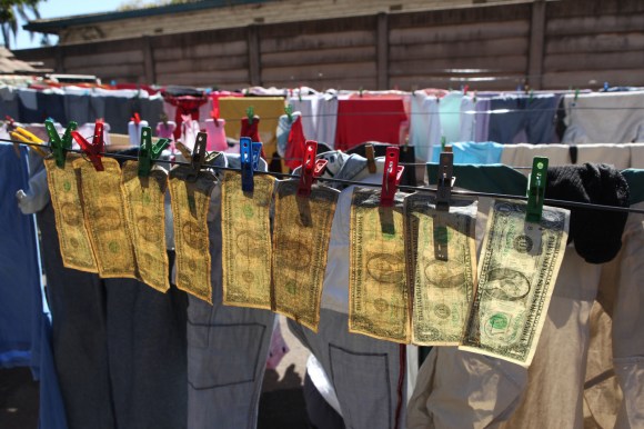 Dollar bills hanging from pegs on a clothes line