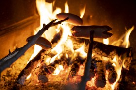 Cervelas en train de griller dans un feu