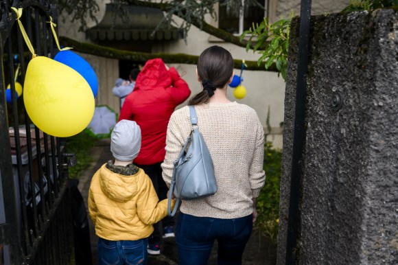 mother and child passing yellow and blue balloon