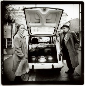 DaniÈlle Huillet and J-M Straub beside a car with the trunk open, filled with film cans