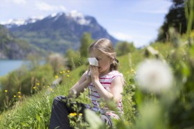 una bambina si soffia il naso in mezzo a un prato fiorito