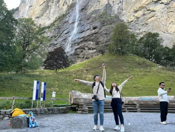 Asiatische Tourist:innen machen vor einem Wasserfall Selfies