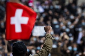 Poing levé devant un drapeau suisse