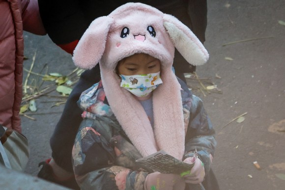 Ein Mädchen in China mit einer Maske und einem Hut, der wie ein Hase aussieht.